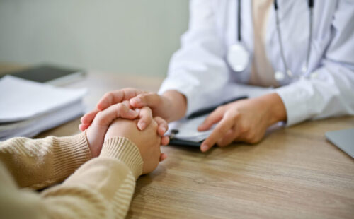 Close up view of doctor touching patient hand, showing empty and kindness. Health care concept